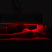 Model receiving a full-body red light therapy session under the illuminated ApolloARC panel in a dark treatment room