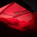 Close-up view of the ApolloARC red light therapy panel illuminated beneath a model, showing LED arrays and bright red light glow