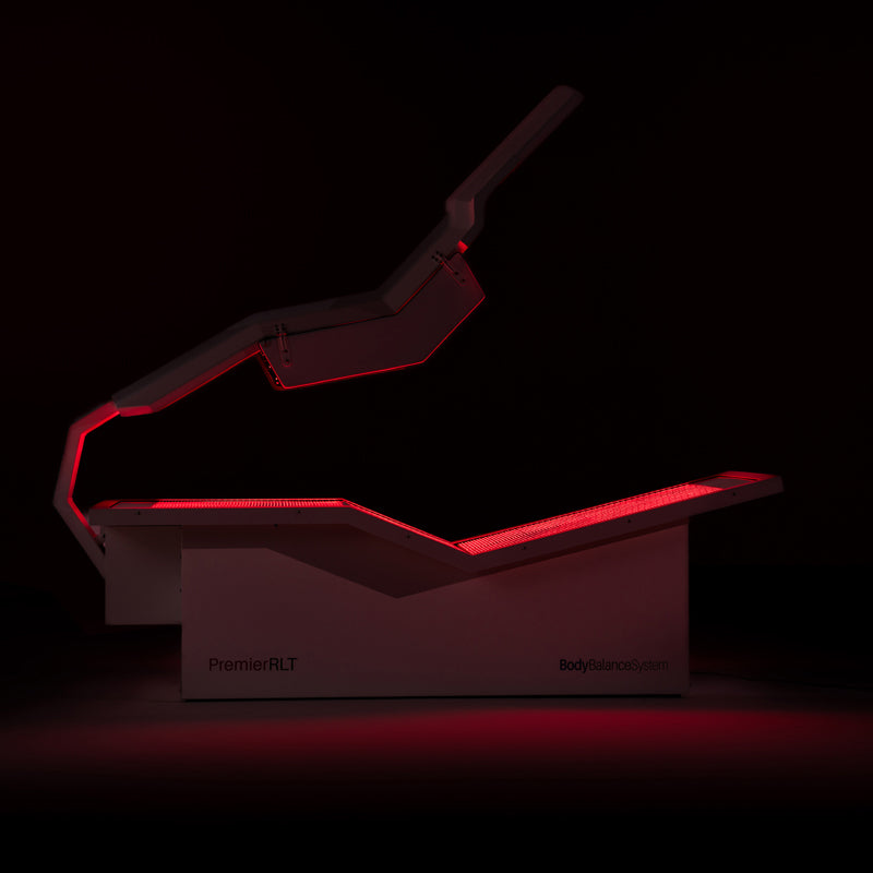 Body Balance System PremierRLT red light therapy bed with canopy open and LEDs glowing on a dark background