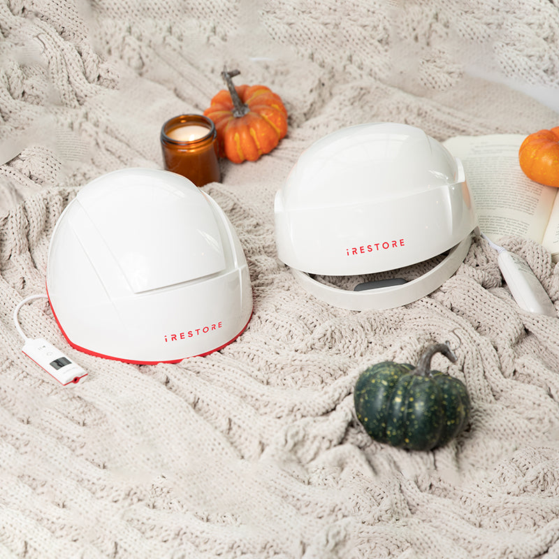 Two iRestore Essential Laser Hair Growth System helmets in festive fall or Thanksgiving-themed background
