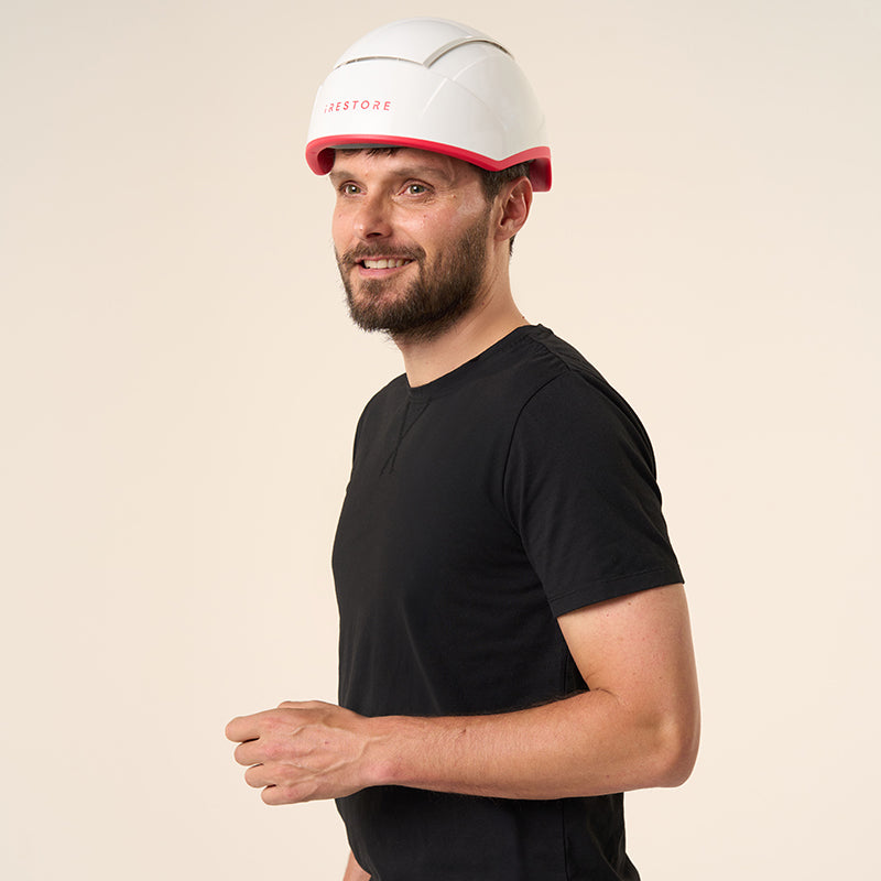 Male model wearing iRestore Professional Laser Hair Growth System helmet, smiling during at-home red light therapy session
