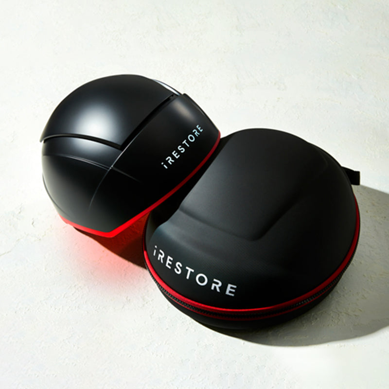 iRestore Elite laser hair growth helmet resting against carrying case on white background
