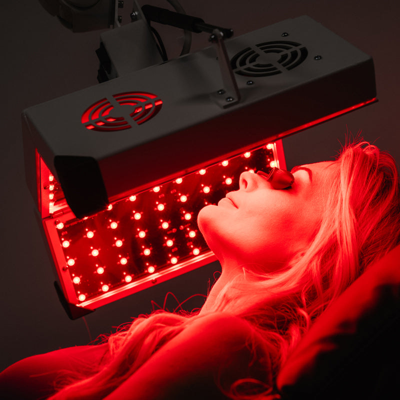 ApolloGlow facial red light therapy panel used during a treatment session on a reclining client
