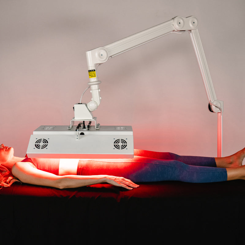 Female model receiving full-body treatment under the Body Balance System ApolloARC red light therapy panel on adjustable arm