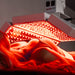 Female model receiving torso treatment under the Body Balance System ApolloARC red light therapy panel with open illuminated LED section