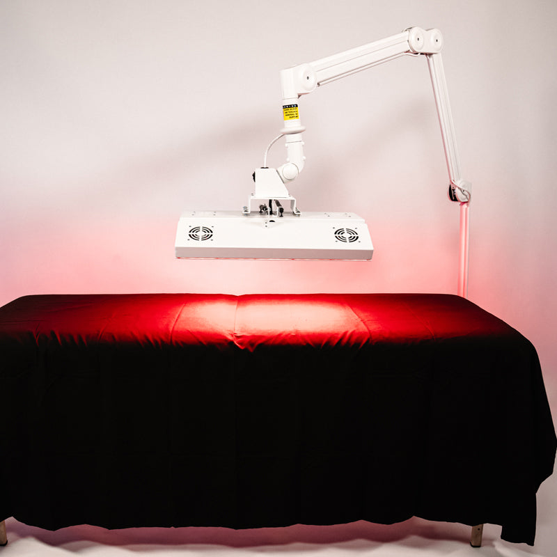 Body Balance System ApolloARC red light therapy panel in lowered position over a treatment table on adjustable arm