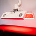 Angled view of the Body Balance System ApolloARC red light therapy panel showing side LED illumination over treatment table
