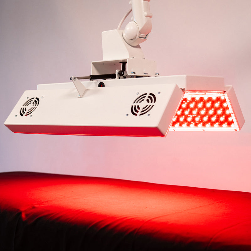 Angled view of the Body Balance System ApolloARC red light therapy panel showing side LED illumination over treatment table