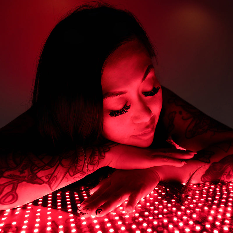 Close-up of female model resting on Body Balance System OvationLlTE red light therapy bed with LEDs illuminated