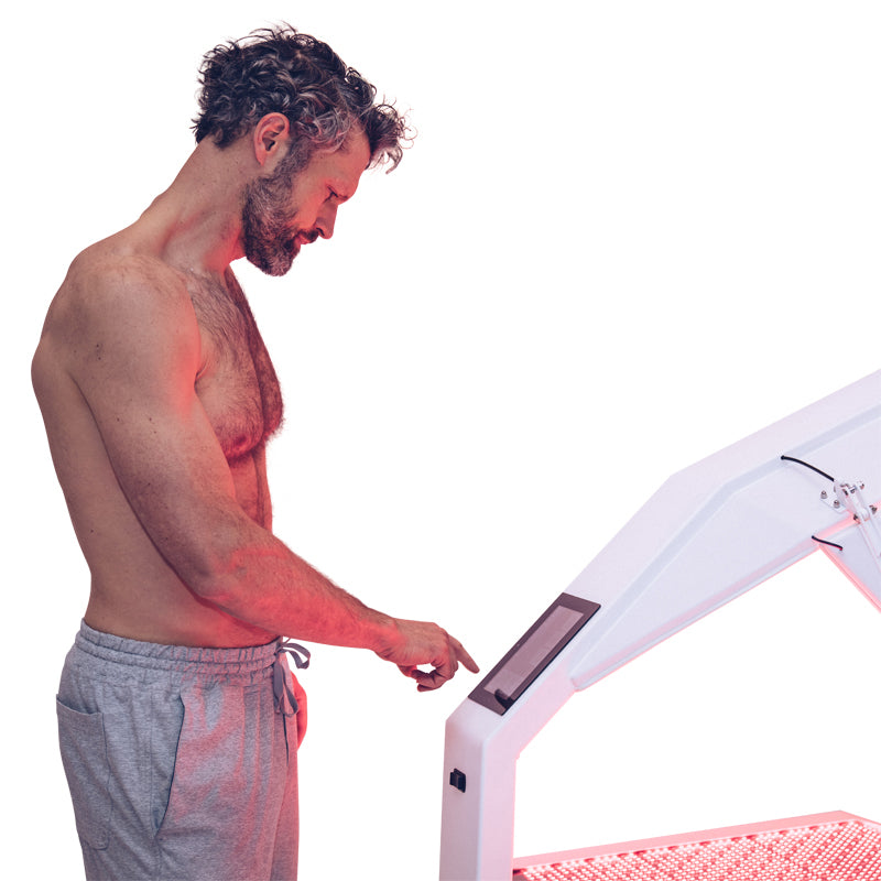 Body Balance System OvationULT Red Light Therapy Bed – male model operating the digital control panel, adjusting red light settings during session setup.