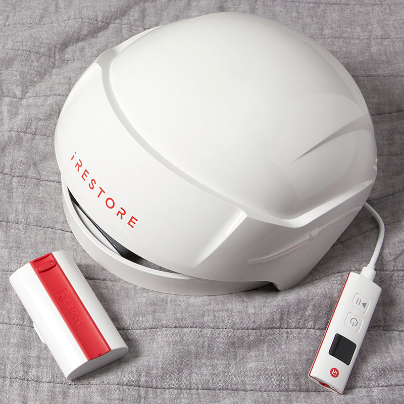iRestore Essential laser hair growth helmet on sheet top view with controller and battery pack.